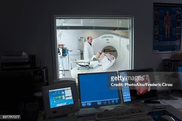 male doctor standing next to female patient having cat scan - cat scan stockfoto's en -beelden