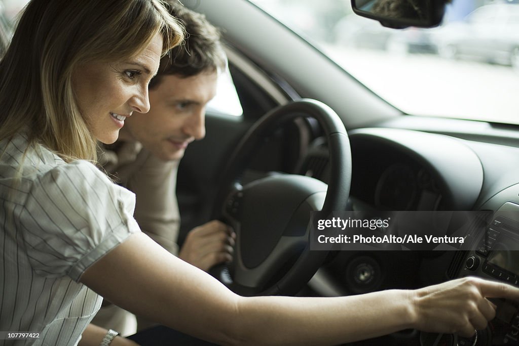 Couple checking out new car interior in dealership showroom