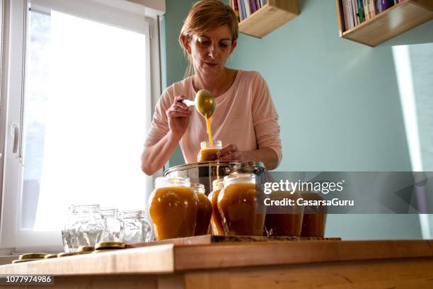 vrouw vullen glazen potten met hete sinaasappeljam - marmalade stockfoto's en -beelden