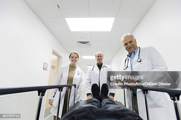 team of doctors looking down at patient on gurney - patient lying down stock pictures, royalty-free photos & images