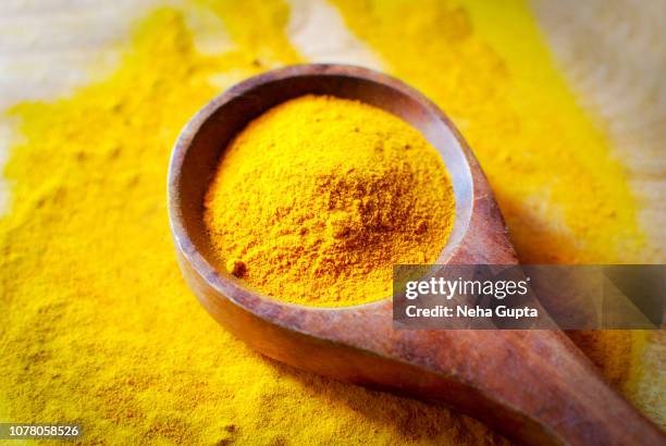 turmeric powder - wooden spoon - curry stock-fotos und bilder