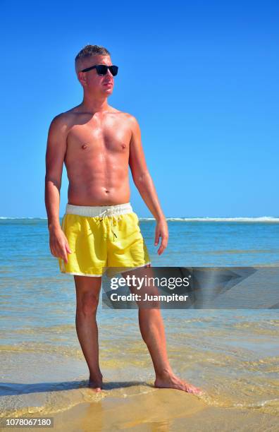 hombre joven disfruta del sol y la playa - hombre joven stock pictures, royalty-free photos & images