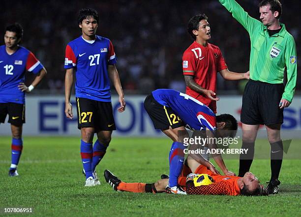 Indonesia's striker Irfan Bachdim talks to referee as Malaysia's goalkeeper Khairul Fahmi lies down on the ground during their second leg final of...