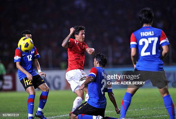 Indonesia's striker Irfan Bachdim challenges Malaysia's players Mochamad Sabre , Mochamad Fadli during their second leg final of the AFF Suzuki Cup...