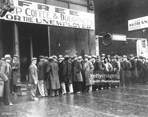 Line of men wait outside a soup kitchen opened durin the depression by mobster Al Capone, Chicago, Illinois, February 1931. The storefront sign reads...