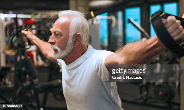 senior man using resistance band in gym - football commentator stock pictures, royalty-free photos & images
