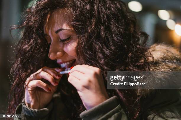 young adult woman rolling a cigarette outdoor in the city at night - marijuana joint imagens e fotografias de stock