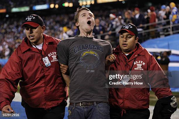 Fan is escorted away after running on the field during the game between the San Diego Chargers and the San Francisco 49ers at Qualcomm Stadium on...