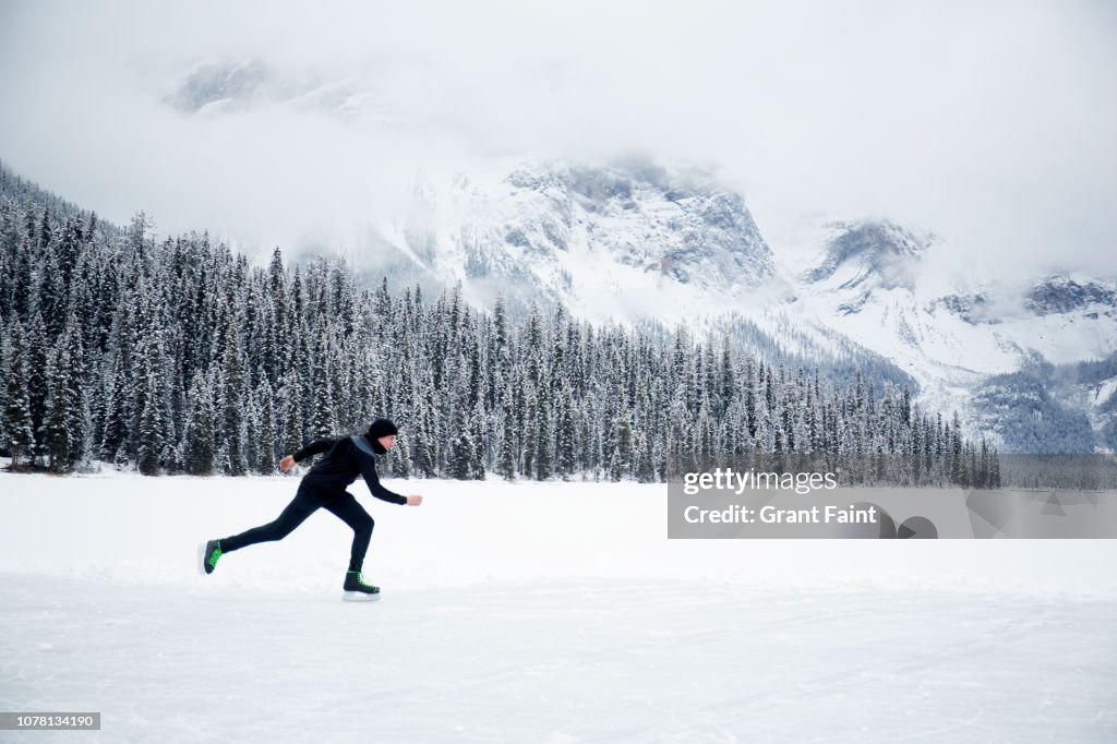 Young man skating on frozen lake.