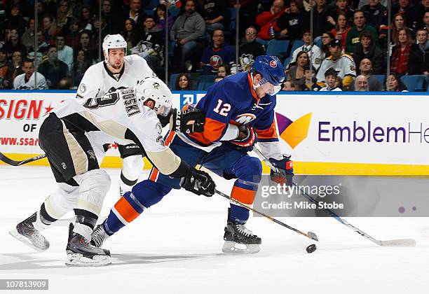 Alex Goligoski of the Pittsburgh Penguins battles for the puck against Josh Bailey of the New York Islanders on December 29, 2010 at Nassau Coliseum...