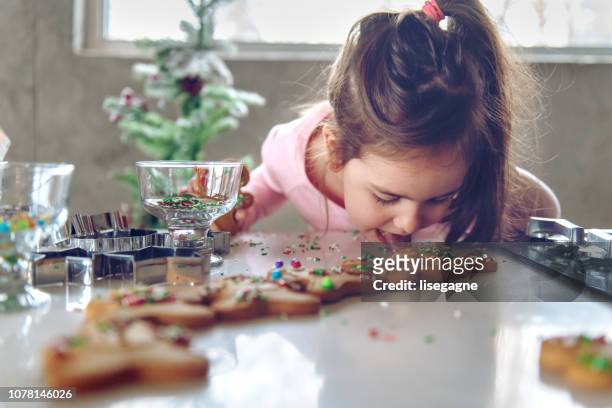 kleines mädchen macht lebkuchen - eating cookies stock-fotos und bilder