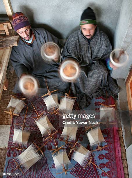 Kashmiri artisans collects pashmina threads on wheels used to make a pashmina shawls, at their workshop December 29, 2010 on the outskirts of...