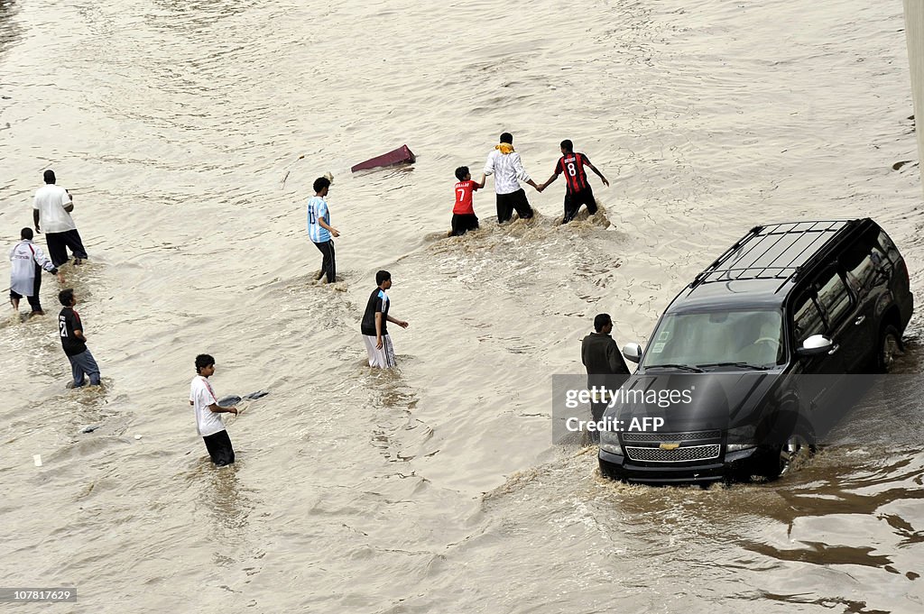 Saudis walk through a flooded street fol