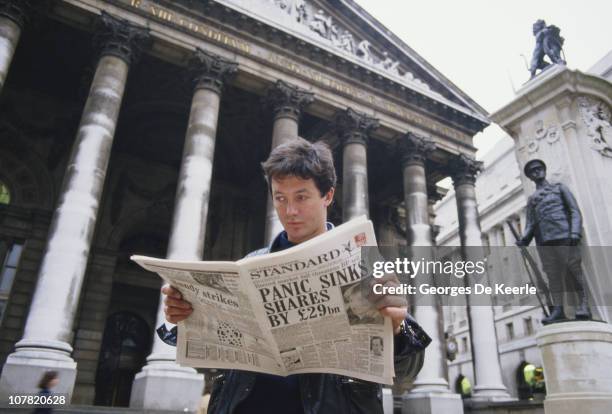 Young man reads a copy of the Evening Standard outside the Royal Exchange in London, with a headline referring to that day's stock market crash,...