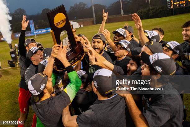 Tufts University players celebrate with the national championship trophy following the Division III Men's Soccer Championship held at the UNCG Soccer...