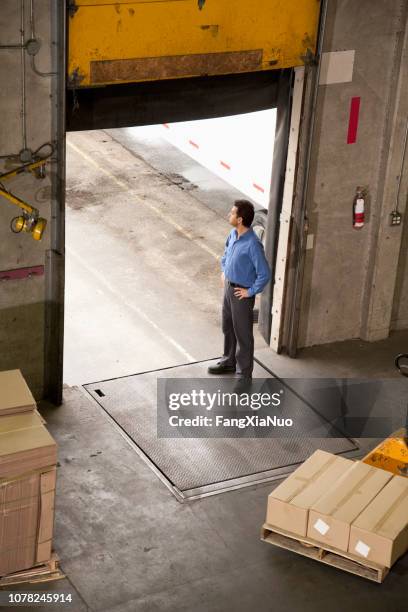 男子站在倉庫門口接受裝運 - loading dock 個照片及圖片檔