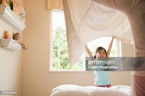 asian daughter and mother making bed at home - role model for children stock pictures, royalty-free photos & images