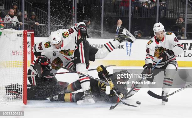 Tomas Nosek of the Vegas Golden Knights slides into Andreas Martinsen and goaltender Corey Crawford of the Chicago Blackhawks as Jan Rutta of the...