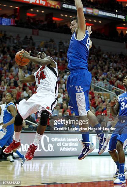 Louisville guard Russ Smith gets caught under Kentucky forward Josh Harrellson as he drives to the basket during game action at KFC Yum! Center in...