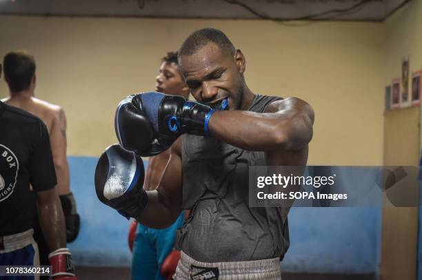 Boxer seen removing his gloves after training at the Kid Chocolate Gym in Havana, Cuba. Cuban boxers are the most successful in the history of...