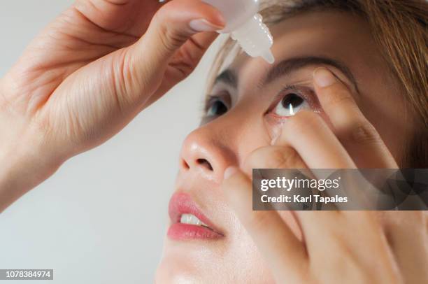 a young woman is applying medicine drops on her eyes - eye drop stock pictures, royalty-free photos & images