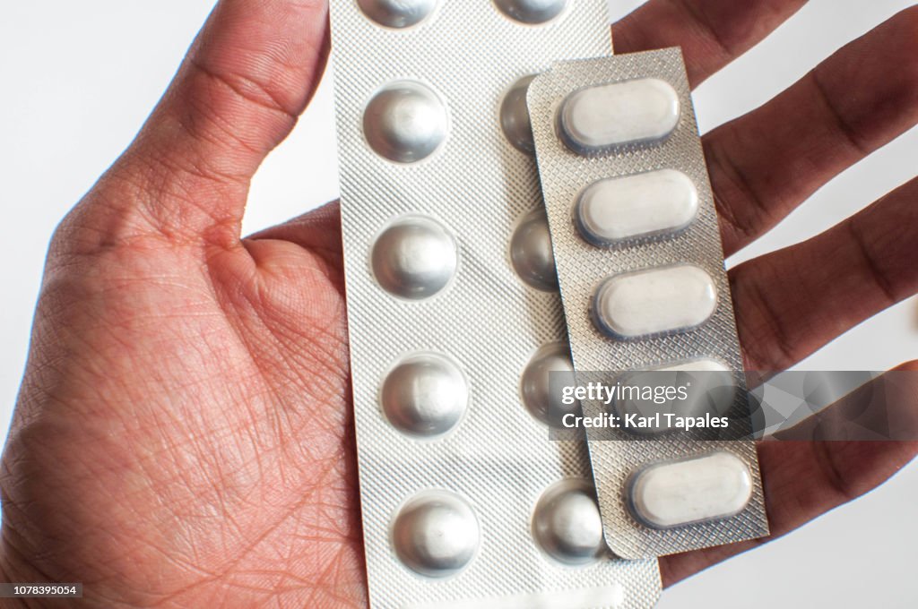 A close-up of a young man is holding a bunch of pills