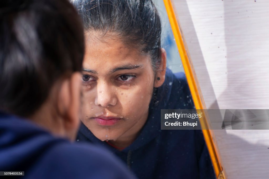 Cute girl washing her face and looking in the mirror