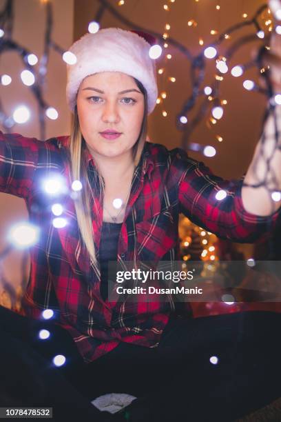 beautiful woman hanging christmas lights. holiday concept - tangled christmas lights stock pictures, royalty-free photos & images