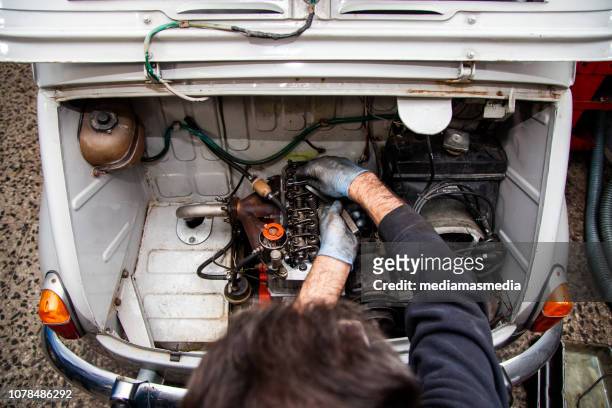 a mechanic repairs the motor of a seat 600 famous vintage car in his workbench in spain - seat 600 stock pictures, royalty-free photos & images