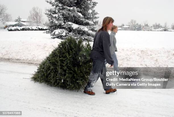Sheri Bosman, left, and her daughter Heather Bosman hall their holiday tree along Miramonte Blvd. To be recycled in Lac Amora Park on Friday.