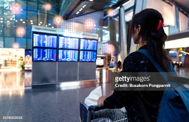 woman at the airport checking for the flight schedule with technology - doha airport stock pictures, royalty-free photos & images