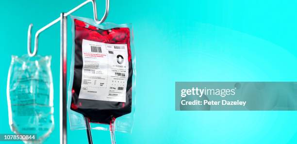 iv blood bag and saline drip on hospital stand with copy space - blutkonserve stock-fotos und bilder