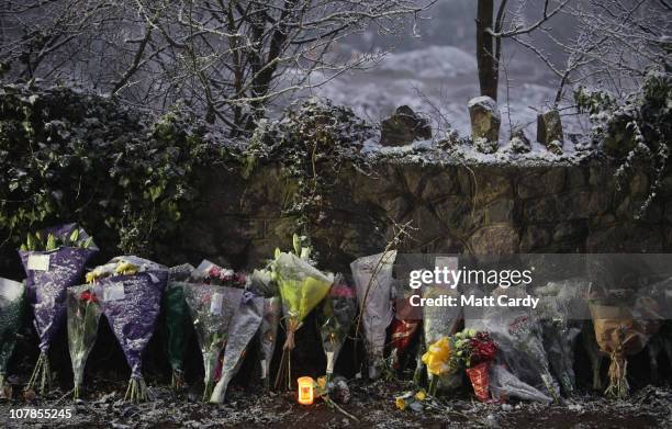 Snow and sleet begins to settle on flowers as a candle burns left in tribute at the spot in Longwood Lane in Failand where Joanna Yeates' body was...