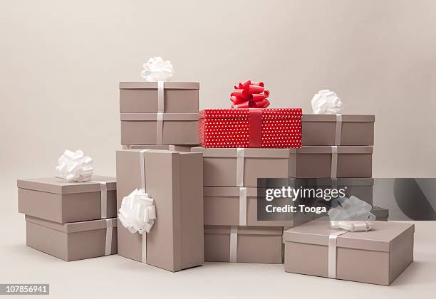 stacks of gray boxes and one red package with bows - present box imagens e fotografias de stock