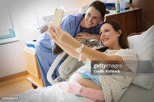 pregnant woman in hospital room taking selfies - muskelkontraktion stock-fotos und bilder