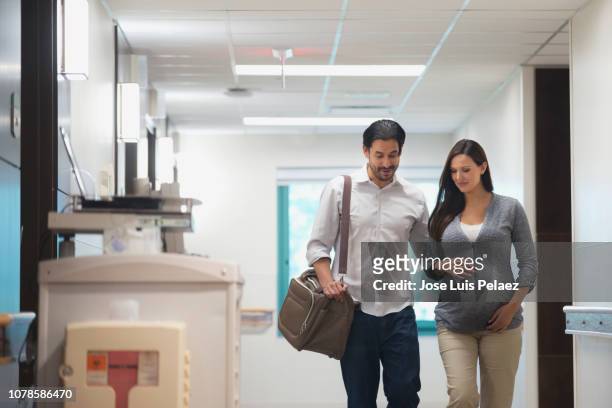 pregnant woman in hospital corridor with husband - baby arrival stock pictures, royalty-free photos & images