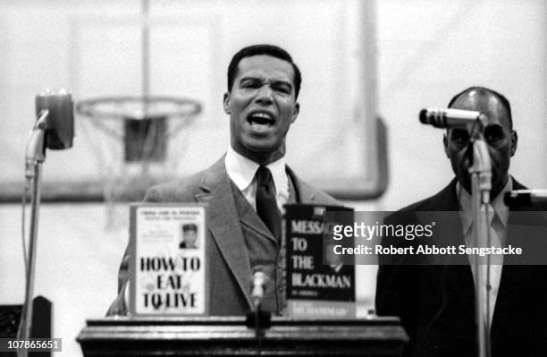 Nation of Islam leader Louis Farrakhan speaks from behind a lecturn at Tennessee State University, Nashville, Tennessee, 1969. On the lecturn are a...
