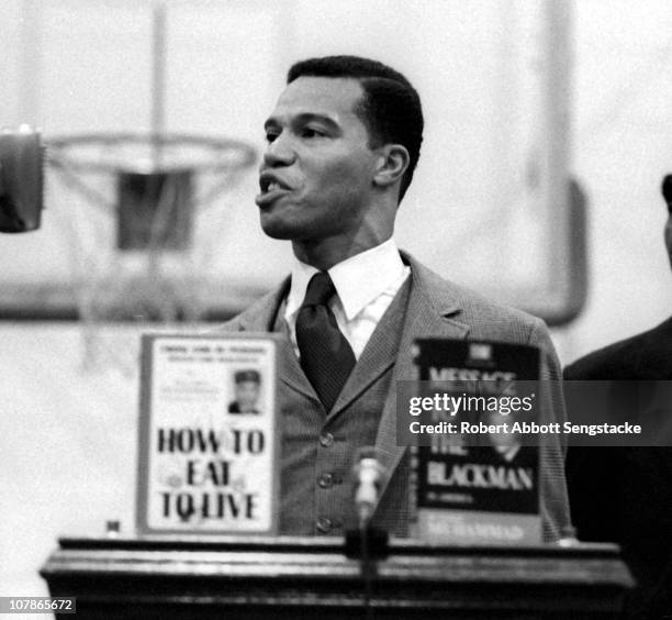 Nation of Islam leader Louis Farrakhan speaks from behind a lecturn at Tennessee State University, Nashville, Tennessee, 1969. On the lecturn are a...