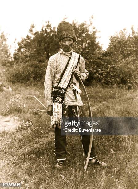 Os Ko Bos, an Osage Indian, standing, full-length, facing front, holding bow and arrows, 1907.