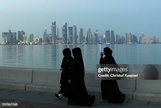 Arabic women walk alongside the skyline of the West Bay area in Doha on January 4, 2011 in Doha, Qatar. The International Monetary Fund recently...