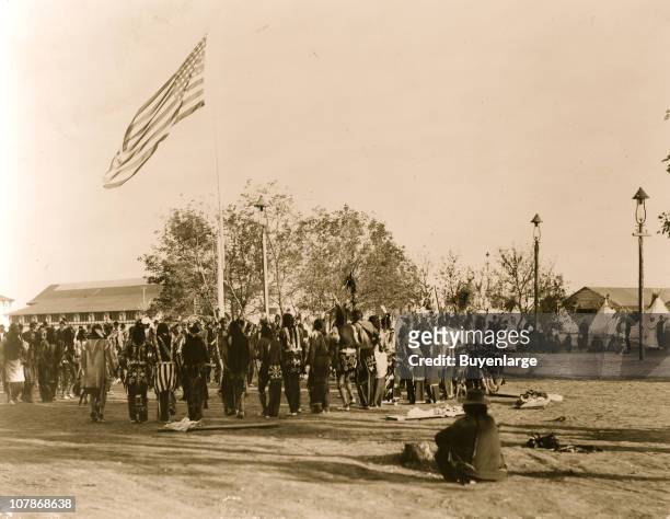Cheyenne and Arapahoe people in circle around flagpole, at the Indian Congress of the Trans-Mississippi and International Exposition, 1898.