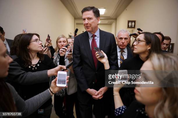 Former Federal Bureau of Investigation Director James Comey is surrounded by reporters after testifying to the House Judiciary and Oversight and...