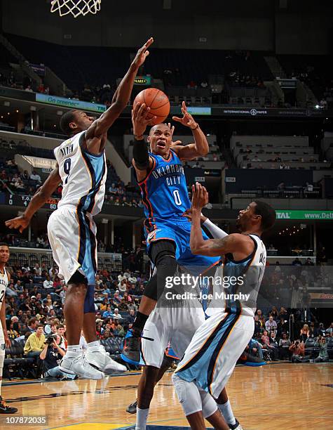 Russell Westbrook of the Oklahoma City Thunder shoots between Tony Allen and Mike Conley of the Memphis Grizzlies on January 4, 2011 at FedExForum in...
