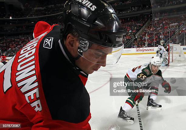 Nick Schultz of the Minnesota Wild checks Jamie Langenbrunner of the New Jersey Devils at the Prudential Center on January 4, 2011 in Newark, New...