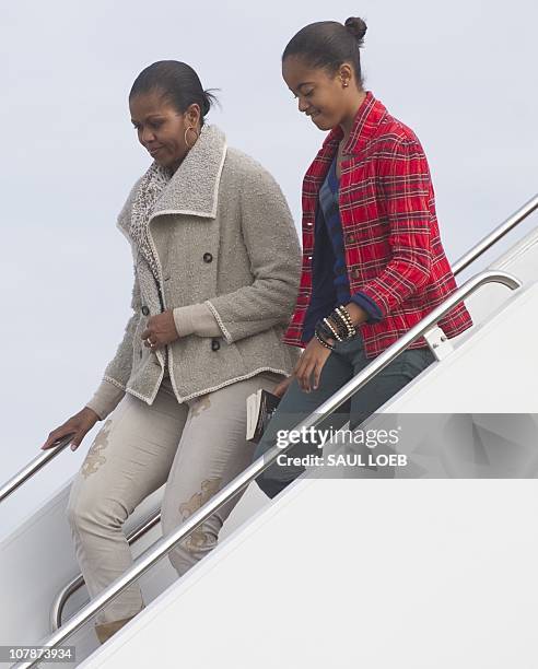 First Lady Michelle Obama and daughter Malia walk down the steps of Air Force One after arriving with US President Barack Obama at Andrews Air Force...