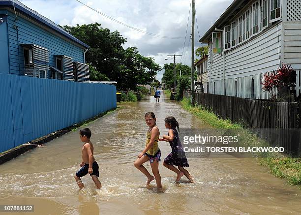 Children cross a flooded street after the swollen Fitzroy River broke its banks and inundated the city of Rockhampton on January 5, 2011. Tens of...
