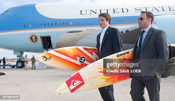 White House staffers Ben Finkenbinder and Nick Shapiro carry surfboards as they walk away from Air Force One after arriving with US President Barack...