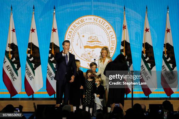 Gavin Newsom gestures to the crowd after being sworn in as governor of California alongside children Montana, Brooklynn, Hunter, Dutch, and wife...