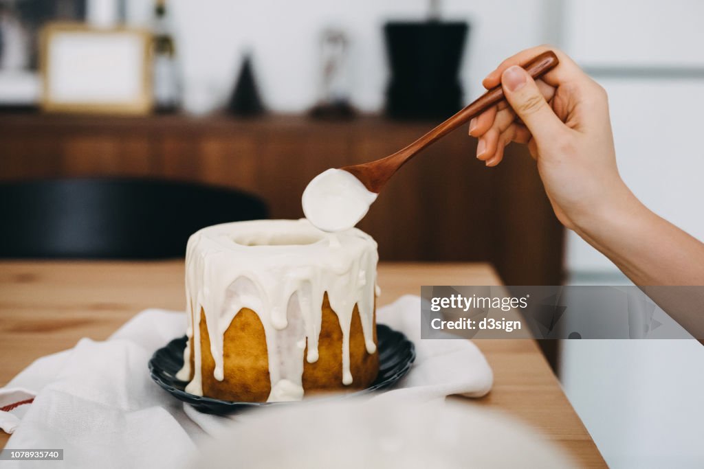 Woman's hand decorating cake with white chocolate