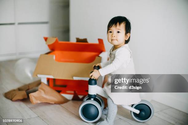 joyful baby girl unwrapped her christmas present and can't wait to ride on her bicycle - training wheels stock pictures, royalty-free photos & images